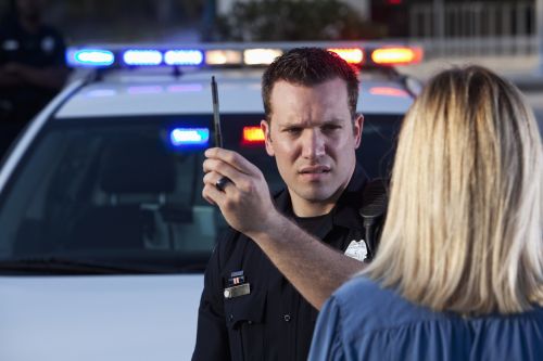 Police officer (20s) conducting sobriety test on woman - field sobriety test concept